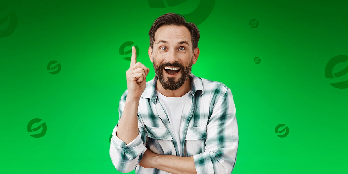 Homem sorridente com barba e cabelo escuro levanta o dedo indicador em gesto de ideia, vestindo camisa xadrez verde e branca sobre camiseta branca; ao fundo, cenário verde vibrante com símbolos circulares estilizados espalhados, que são a logo da Odds Scanner