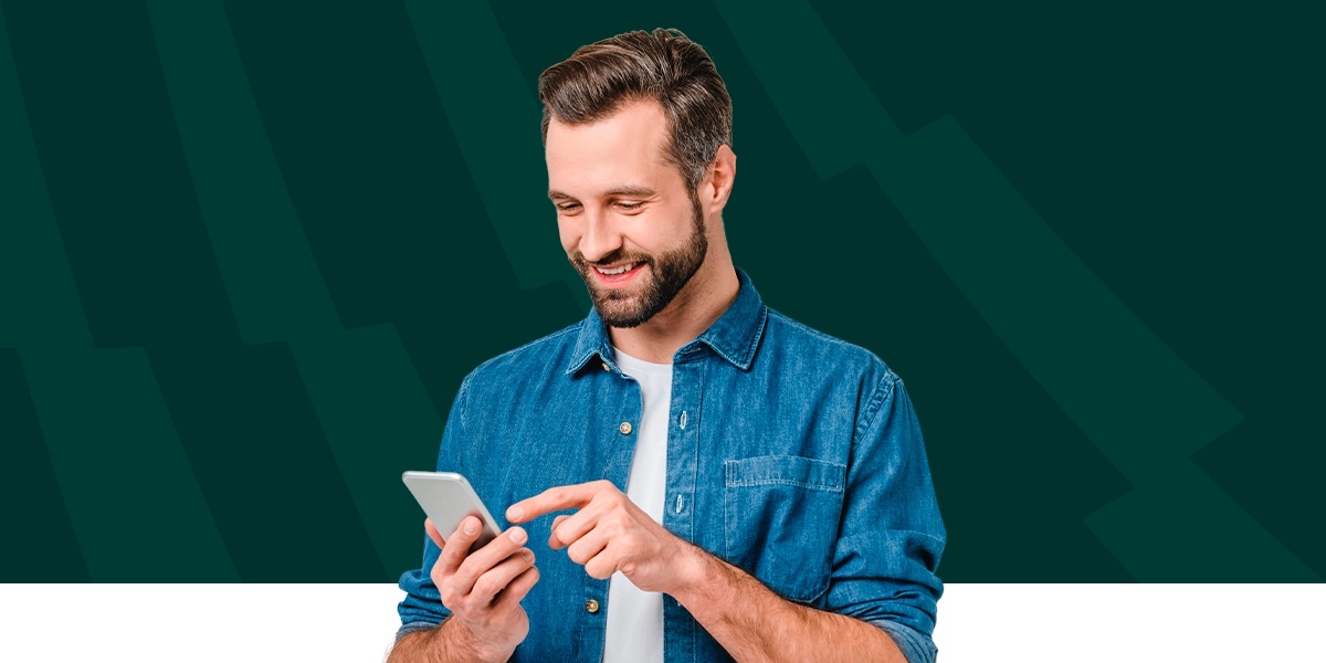 Imagem mostra homem sorrindo ao utilizar um smartphone