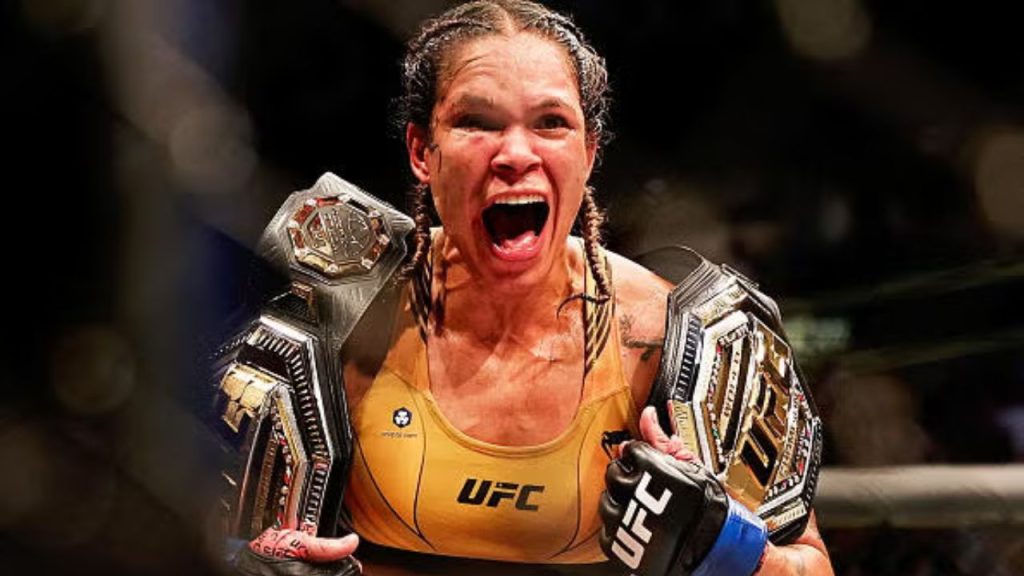 Imagem da lutadora Amanda Nunes, com seus dois cinturões conquistados sem derrotas, um feito histórico na história do UFC, que apenas outros quatro atletas alcançaram